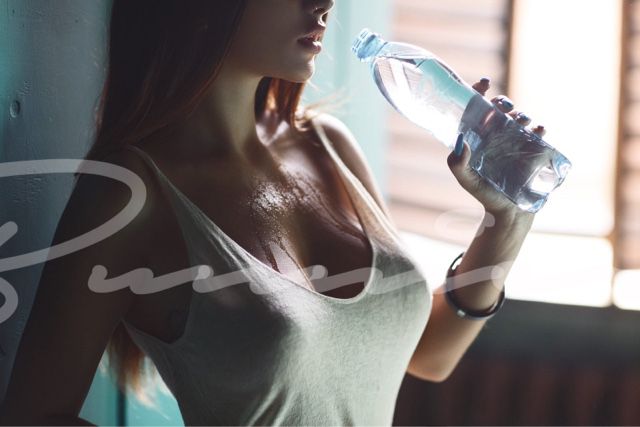 Annamae in a white wifebeater while drinking a bottle of water